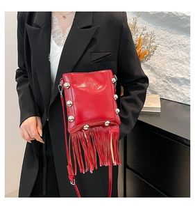 Detail of red bucket bag with metallic silver rivets and long tassel fringe details