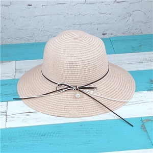 Detail of hand-woven straw hat texture with pearl charm and bow ribbon decoration