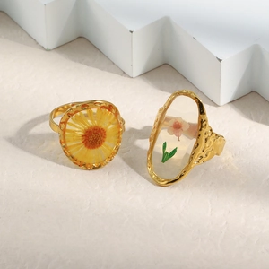 Detailed close-up of vintage gold rings with real dried flowers in transparent resin
