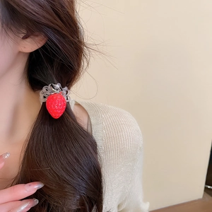 Détail d'une breloque fraise en peluche sur un élastique à cheveux spirale transparent