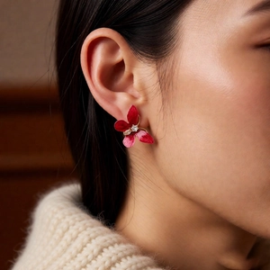 Détail d'une boucle d'oreille fleur rouge vintage en émail avec un centre en zircon