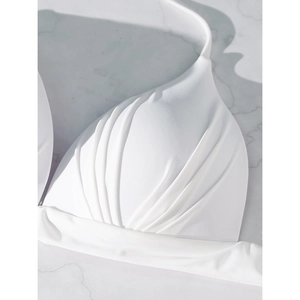 Detailed close-up of white ruched bikini top with elegant halter neck straps and fine stitching