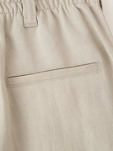 Detailed view of beige twill pants featuring a welt back pocket and elastic waistband
