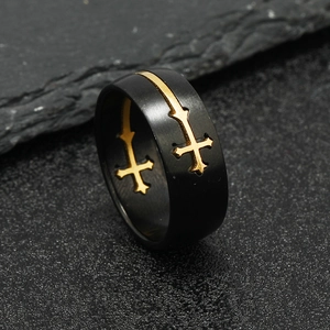 Men's black matte stainless steel ring with gold cross inlay on dark stone background