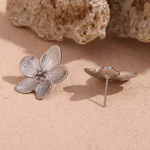 Macro shot of silver flower earrings showing five-petal design and metal texture
