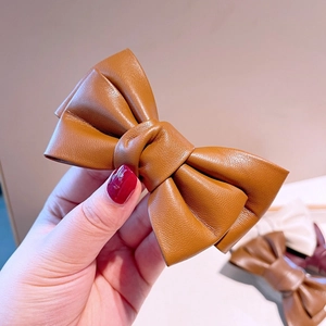 Détail de la pince à cheveux noeud en cuir marron caramel avec texture grainée