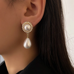 Détail d'une boucle d'oreille vintage en perle avec clou fleuri doré sur un modèle