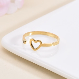 Polished gold heart-shaped open ring with small crystal stone on white tray