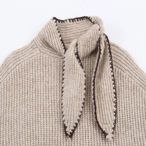 Détail macro du pull en tricot avoine avec texture côtelée et col à nouer avec bordure