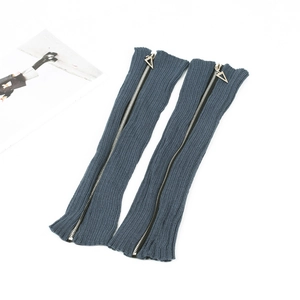 Close-up of blue ribbed knit leg warmers featuring black zippers and metal sliders