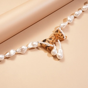 Detail of baroque pearl necklace featuring a resin leopard print bow pendant on display