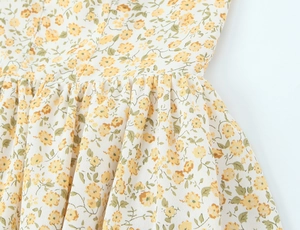 Détail de la robe florale montrant des fleurs jaunes et la texture plissée à la taille