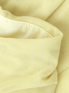 Close-up of elegant light yellow mesh fabric detail with fine texture and neat stitching