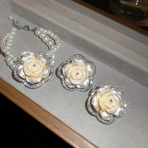Detailed view of camellia pearl bracelet and earrings set with crystal inlay on beige velvet