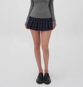 Detailed view of dark blue plaid pleated mini skirt with knit sweater and loafers