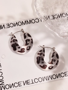 Detail of C-shaped leopard resin earrings with silver metal clasps and glossy texture