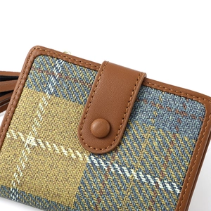 Detail shot of brown leather trim, blue-yellow plaid fabric and snap closure on coin purse