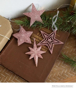 Detail of pink glitter star ornaments with ribbons on a festive background