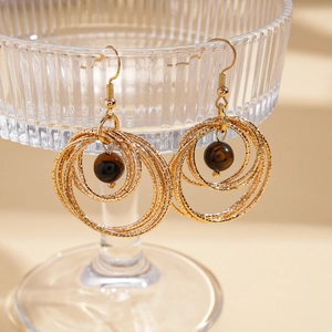 Detailed shot of bohemian multilayer gold hoop earrings with brown tiger eye stones