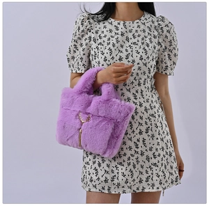 Faux rabbit fur purple tote bag featuring a gold deer head charm worn by a model
