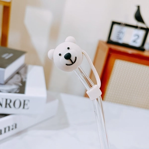 Detail of cute white bear silicone straw cover on a glass straw in a cozy home setting