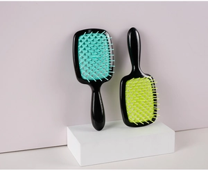 Detail showing two hollow-out hair brushes with black handles and colorful bristles on blocks