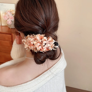 Detailed view of peach fabric flower hair clip worn by a model in a cozy setting