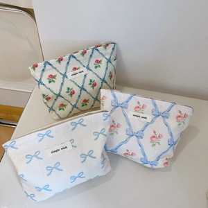 Détail de trousses à maquillage fleuries avec rubans bleus, motifs roses et étiquette