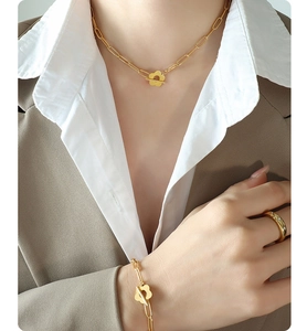 Detailed view of 18k gold plated chunky chain necklace and bracelet with flower OT buckle
