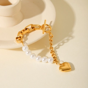 Golden pearl heart pendant chain bracelet with OT toggle clasp on minimalist background