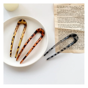Close-up of three acetate U-shaped hairpins with leopard print on a vintage book