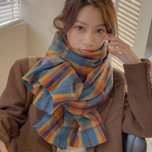 Winter plaid scarf with blue and orange check pattern worn by a model in soft window light