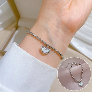Detail of silver titanium steel bead bracelet with heart mother of pearl charm on wrist