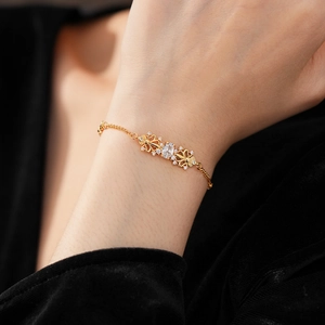 Dettaglio del bracciale iris dorato con zircone ovale sul polso di una modella