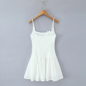 White embroidered hollow-out mini dress with thin straps and ruffled hem on a hanger