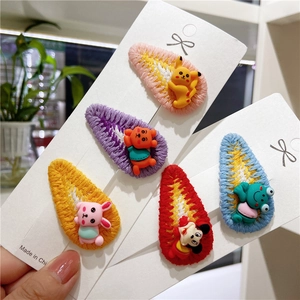 Close-up of five handmade knitted hair clips with cartoon embroidery on display card