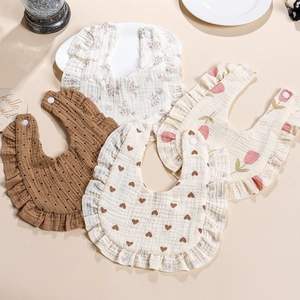 Detail of four soft 4-layer muslin cotton baby bibs with floral prints and ruffle edges
