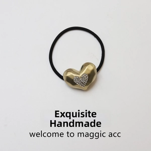 Detail of a matte gold heart hair tie with shimmering rhinestones and black elastic band