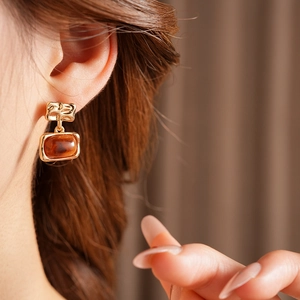 Vue macro de boucles d'oreilles carrées en résine plaquée or portées par un mannequin