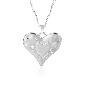 Macro shot of silver heart pendant with textured outer layer and smooth inner core