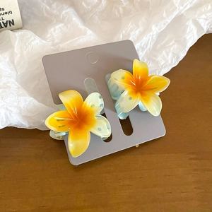 Macro shot of yellow gradient plumeria hair clips on a textured background