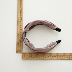 Cerchietto a nodo rosa in tessuto setoso con righello per riferimento dimensioni