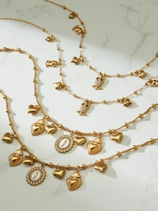Detail of gold pendants including owls and hearts on elegant marble background