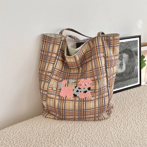 Close-up of the vintage plaid tote bag with pink cartoon cat embroidery and soft texture