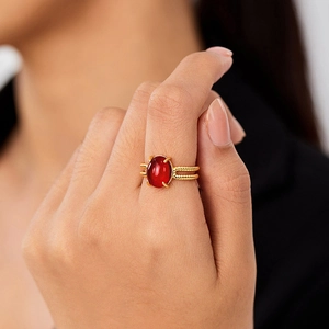 Golden French style ring with oval red gemstone and twisted rope band detail on hand