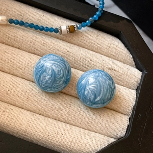 Élégantes boucles d'oreilles boules bleu clair marbré sur un plateau à bijoux