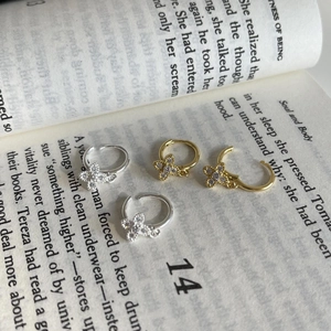 Macro view of S925 silver hoop earrings with zircon clover charms on a vintage book