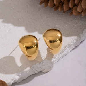 Close-up of golden teardrop stud earrings with polished finish on a natural stone base