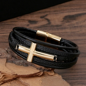 Detail of multi-layer black leather bracelet with polished gold cross and magnetic clasp