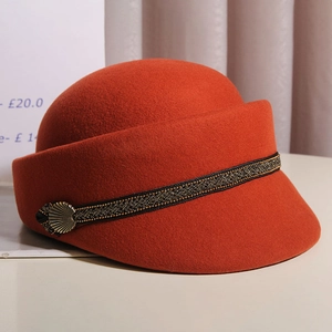 Detailed close-up of burnt orange wool felt hat with decorative black gold braided band